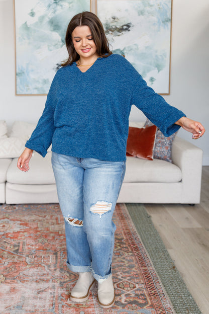 Woman wearing a blue sweater and jeans in a living room setting