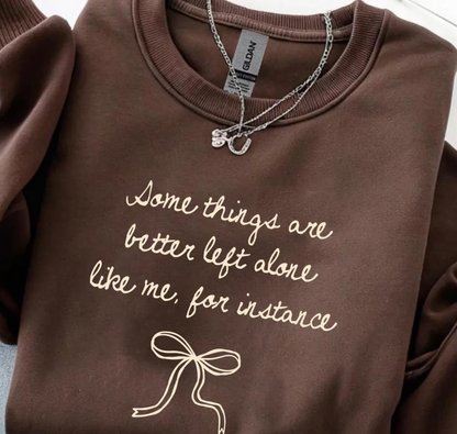 Brown sweatshirt with text and a bow design, featuring a Gildan tag.