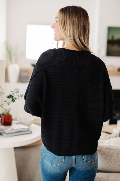 Person wearing a black sweater and blue jeans in a living room setting