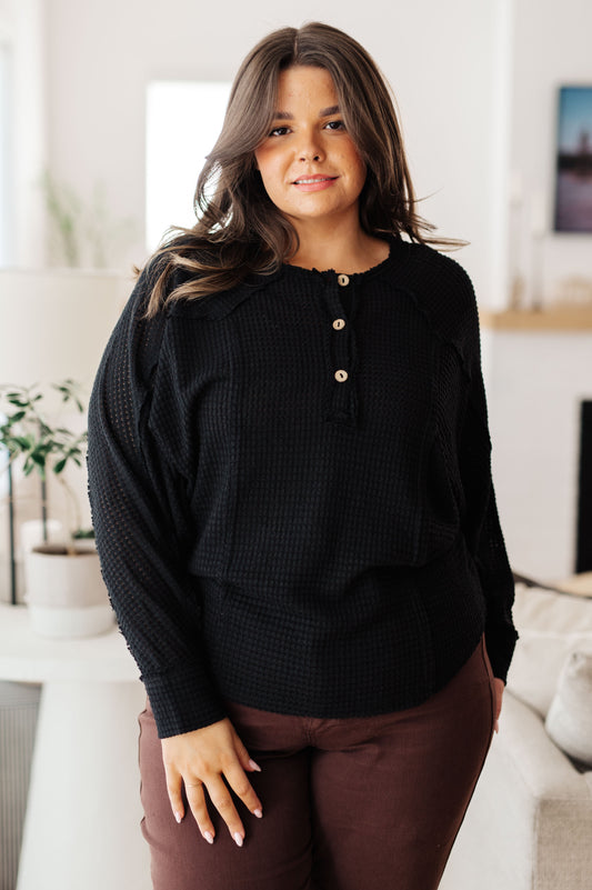 Woman wearing a black blouse with a blurred indoor background