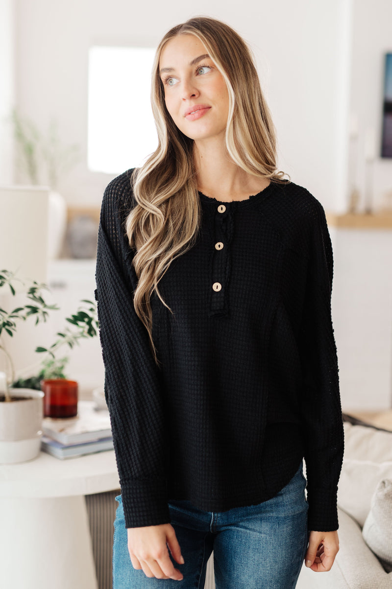 Woman wearing a black sweater with buttons in a bright room
