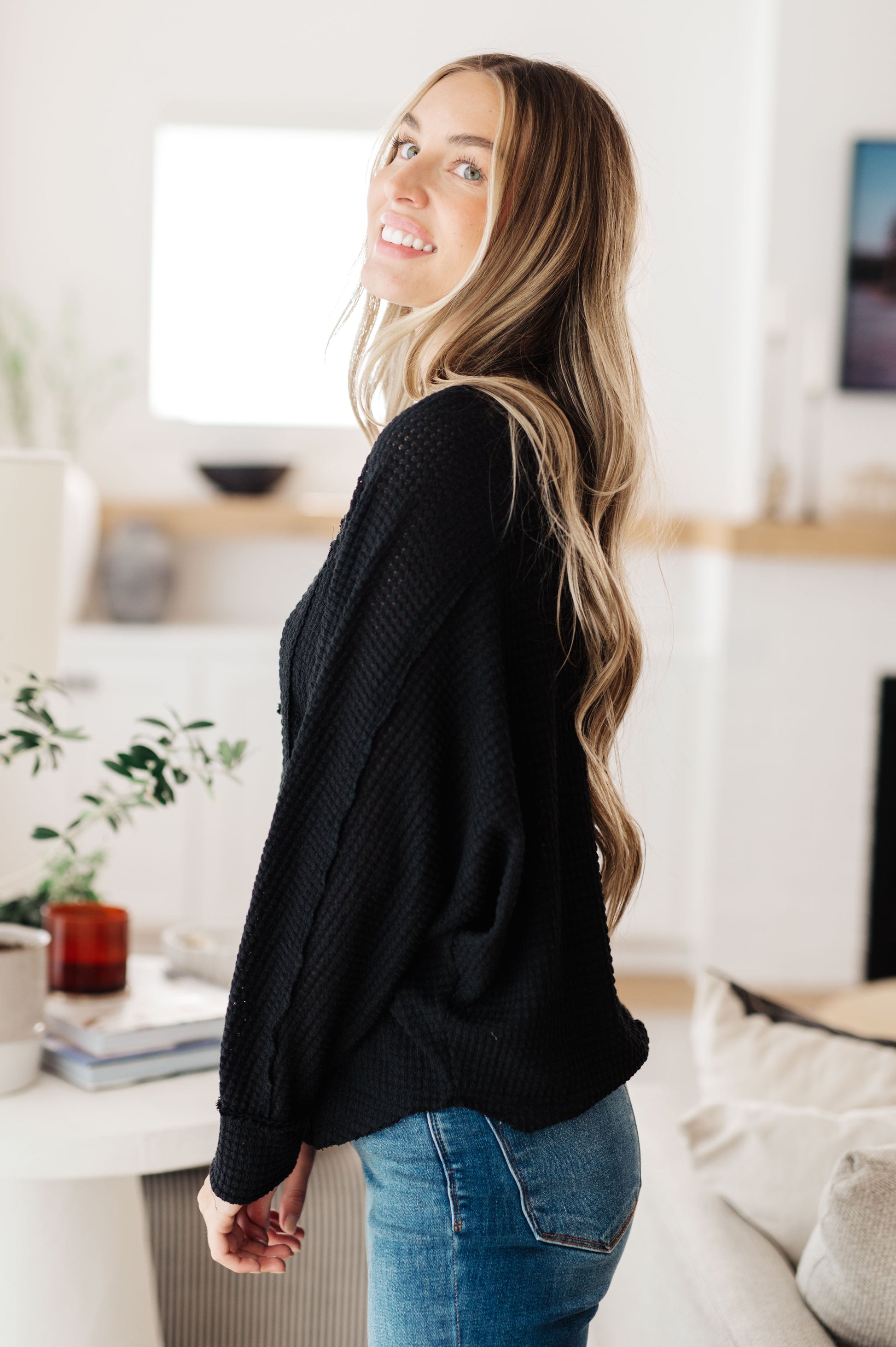 Woman wearing a black sweater and blue jeans in a living room setting