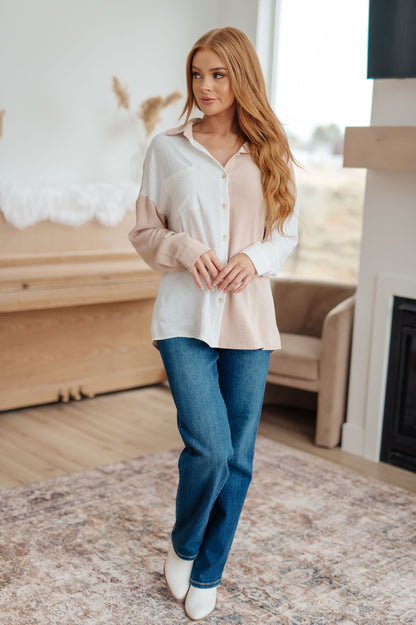 Woman wearing a white blouse and blue jeans standing in a living room.