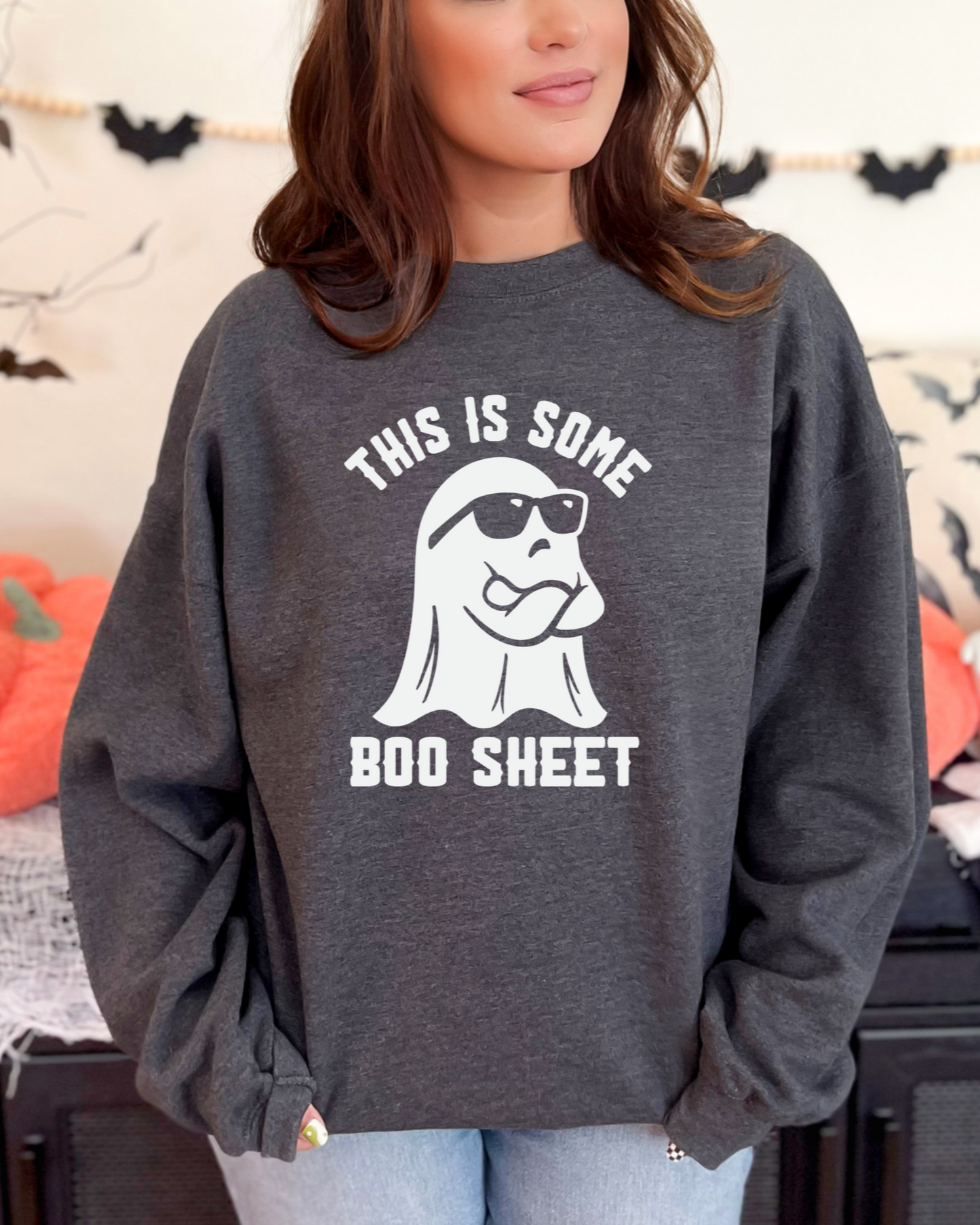 Person wearing a dark gray sweatshirt with a ghost graphic and text in a Halloween-themed setting.