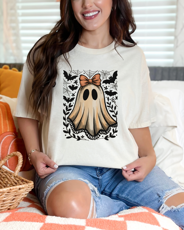 Woman wearing a white t-shirt with a ghost design, sitting on a couch.