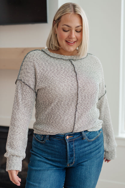 Woman wearing a gray sweater and blue jeans indoors