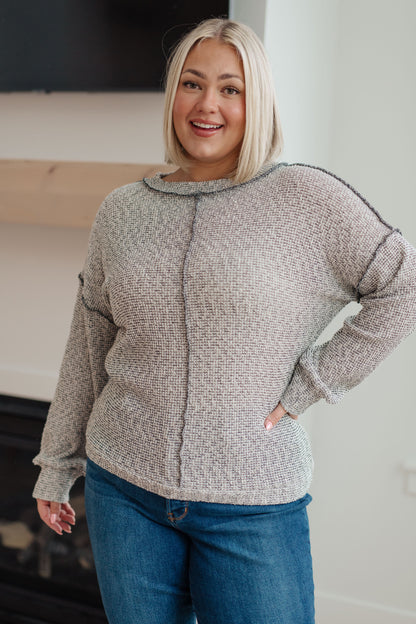 Woman wearing a gray sweater and blue jeans indoors