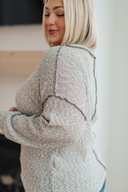Woman wearing a textured gray sweater indoors