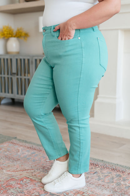 Person wearing turquoise jeans and white sneakers in a home setting