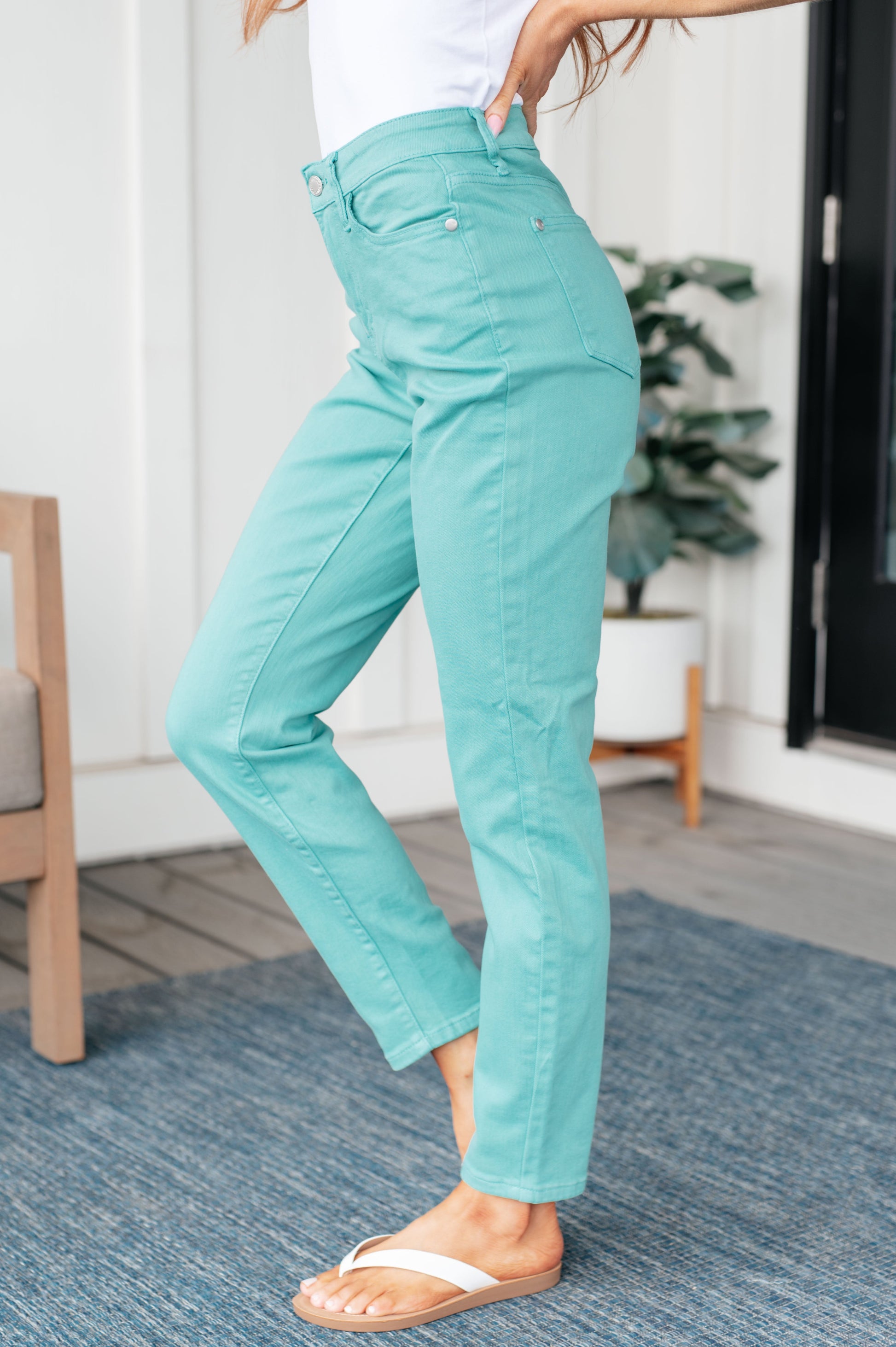 Person wearing turquoise pants standing on a blue rug indoors.