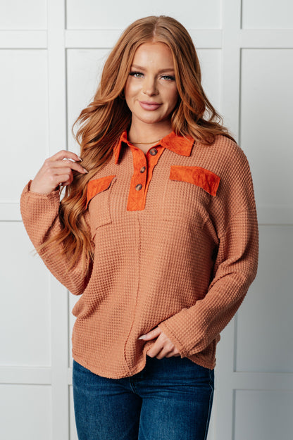 Woman wearing a brown textured shirt with orange accents against a white background