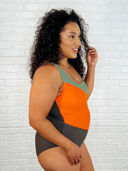 Woman wearing a colorful swimsuit against a white brick wall