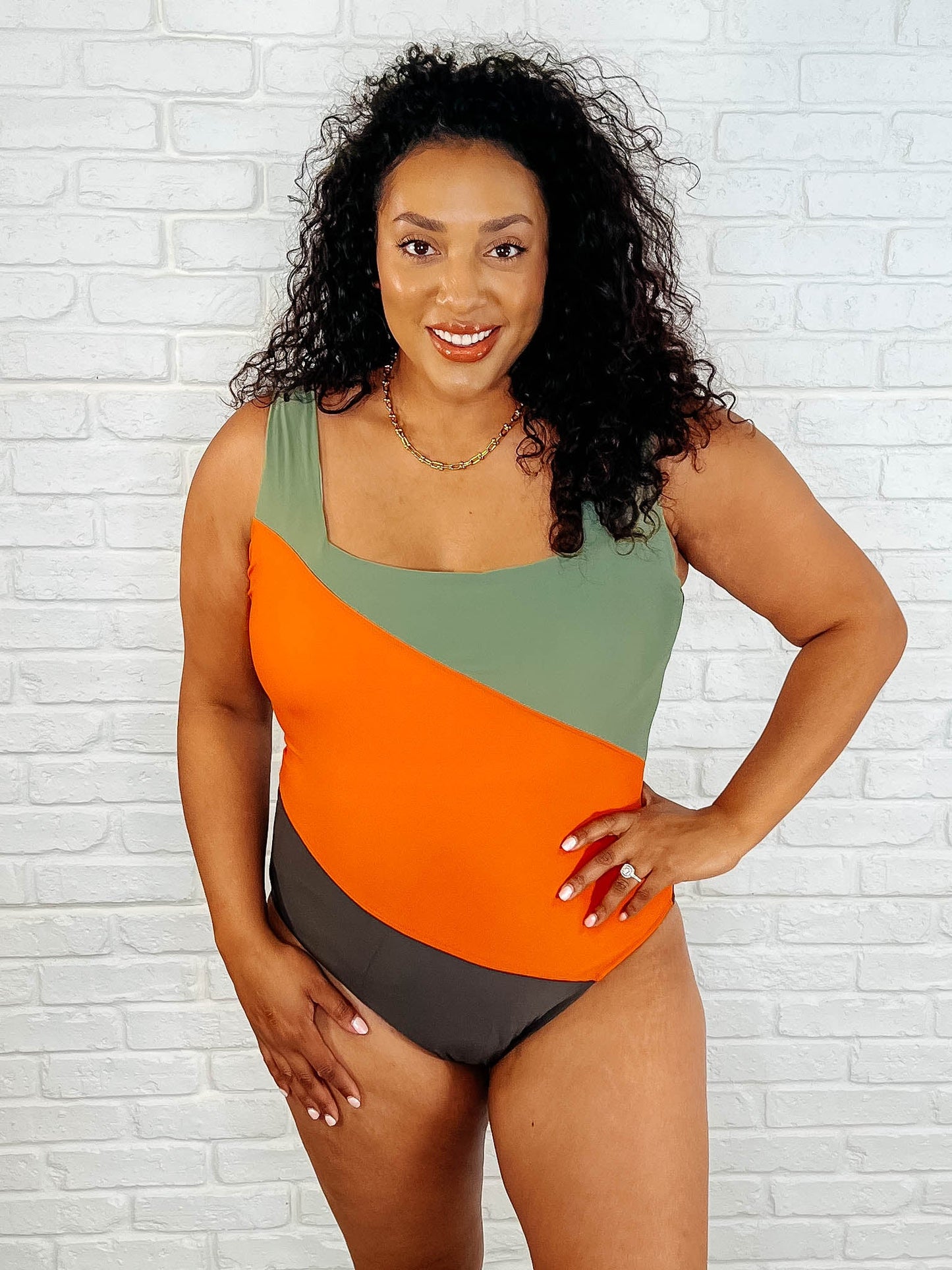 Woman wearing a colorful swimsuit against a white brick wall