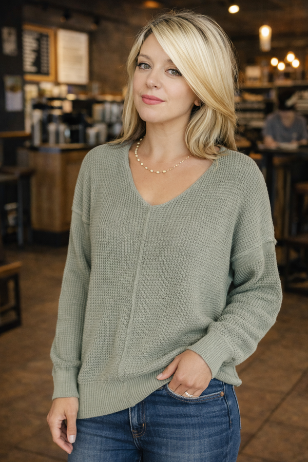 Woman wearing a green sweater in a coffee shop setting