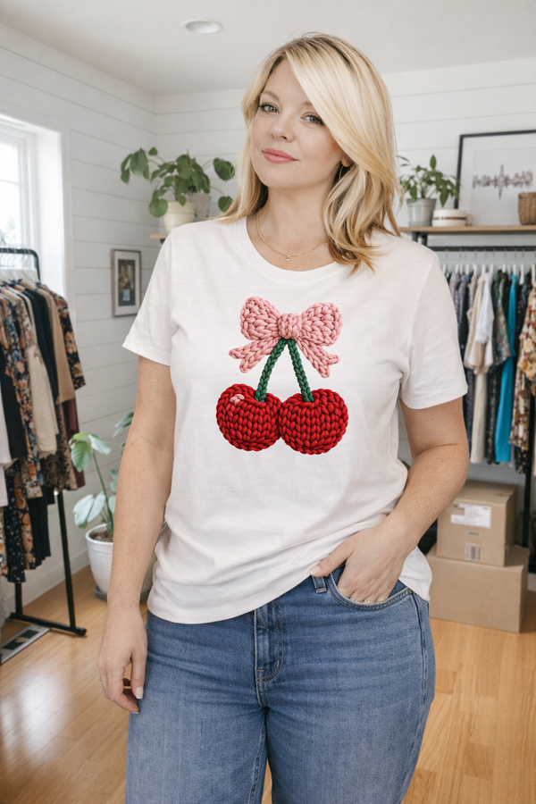 Woman wearing a white t-shirt with a red and pink graphic design in a clothing store.