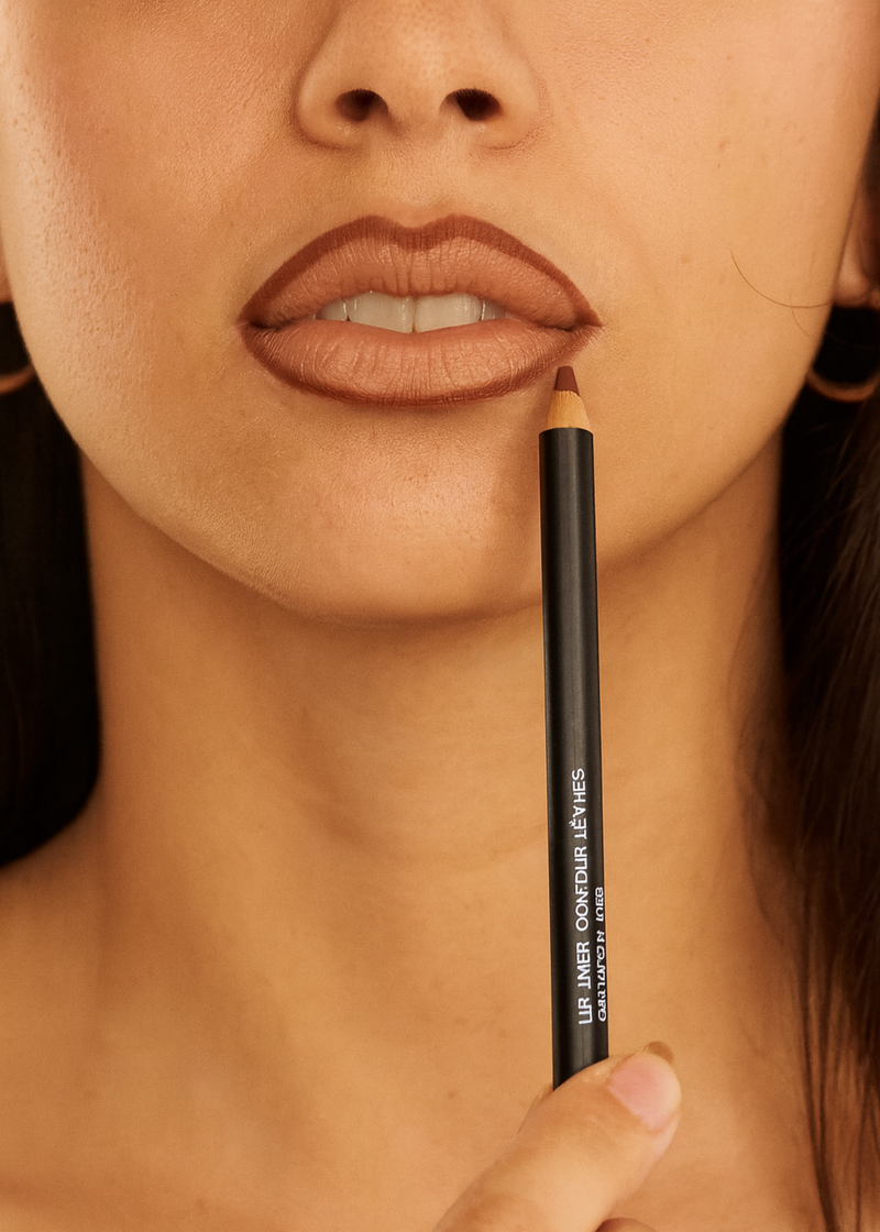 Close-up of a person holding a lip pencil near their lips