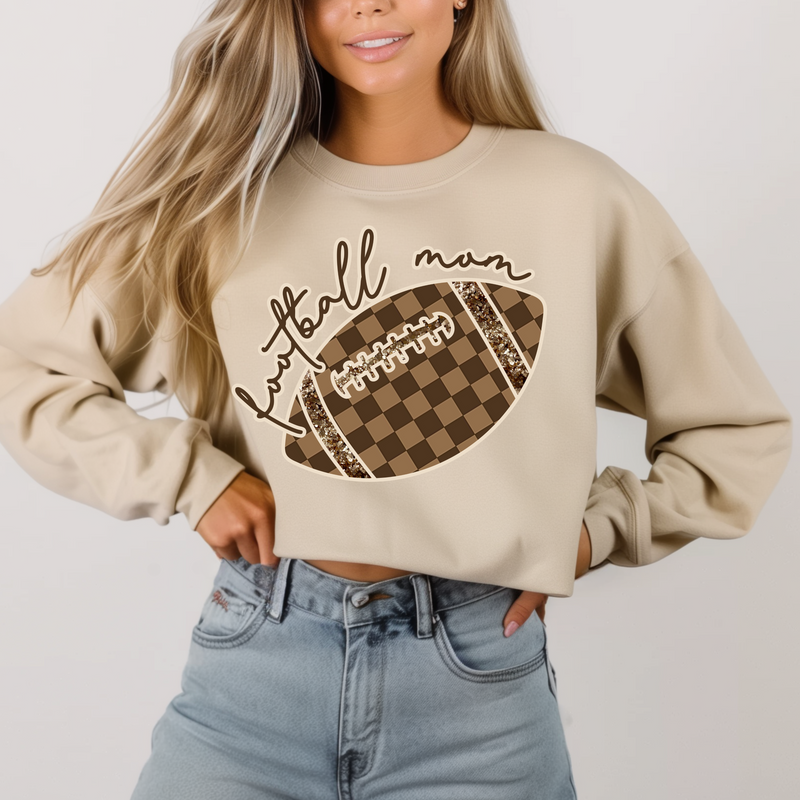 Woman wearing a beige sweatshirt with a football design and text on a plain background