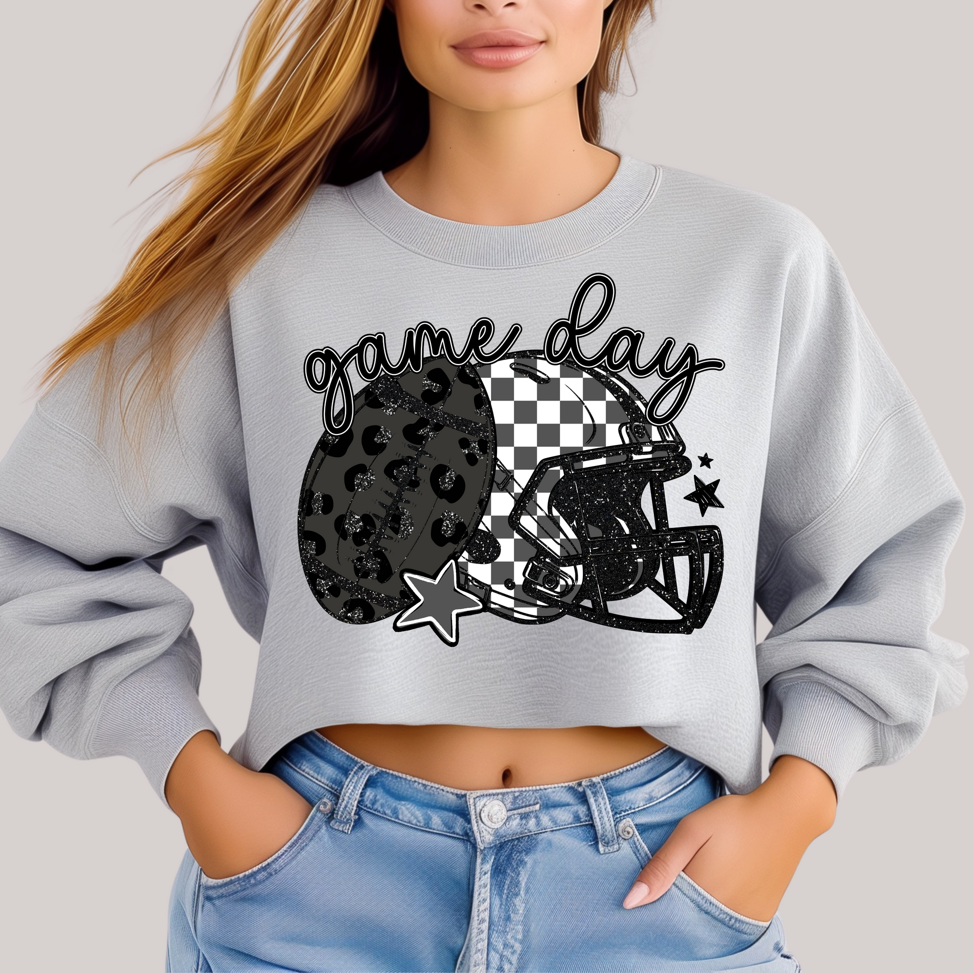 Person wearing a gray sweatshirt with a 'game day' design featuring a leopard print helmet and checkered pattern.
