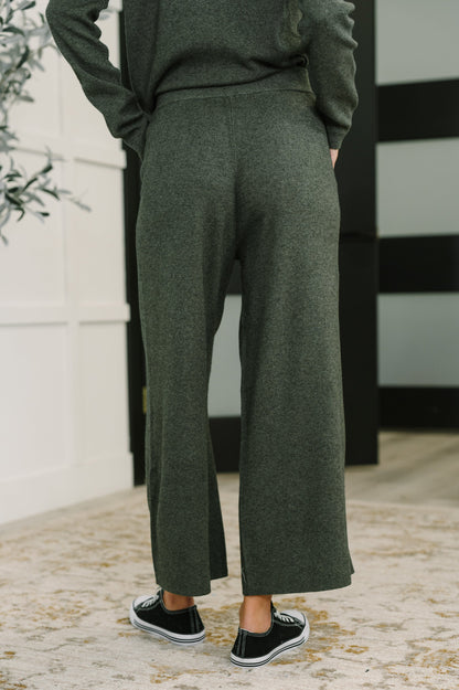 Person wearing green pants and a dark sweater with a blurred background