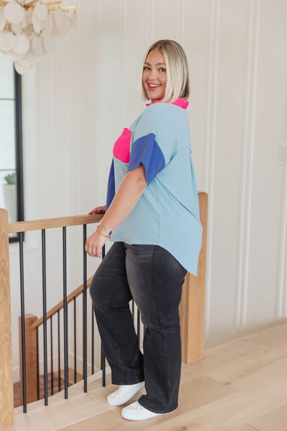 Woman wearing a colorful shirt and dark pants standing on a staircase.