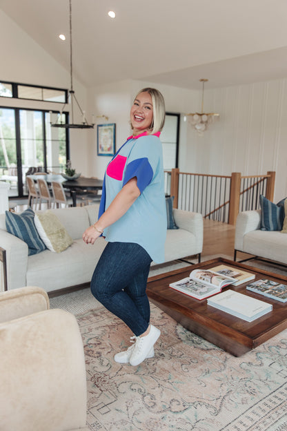 Woman in a living room wearing a colorful shirt and jeans