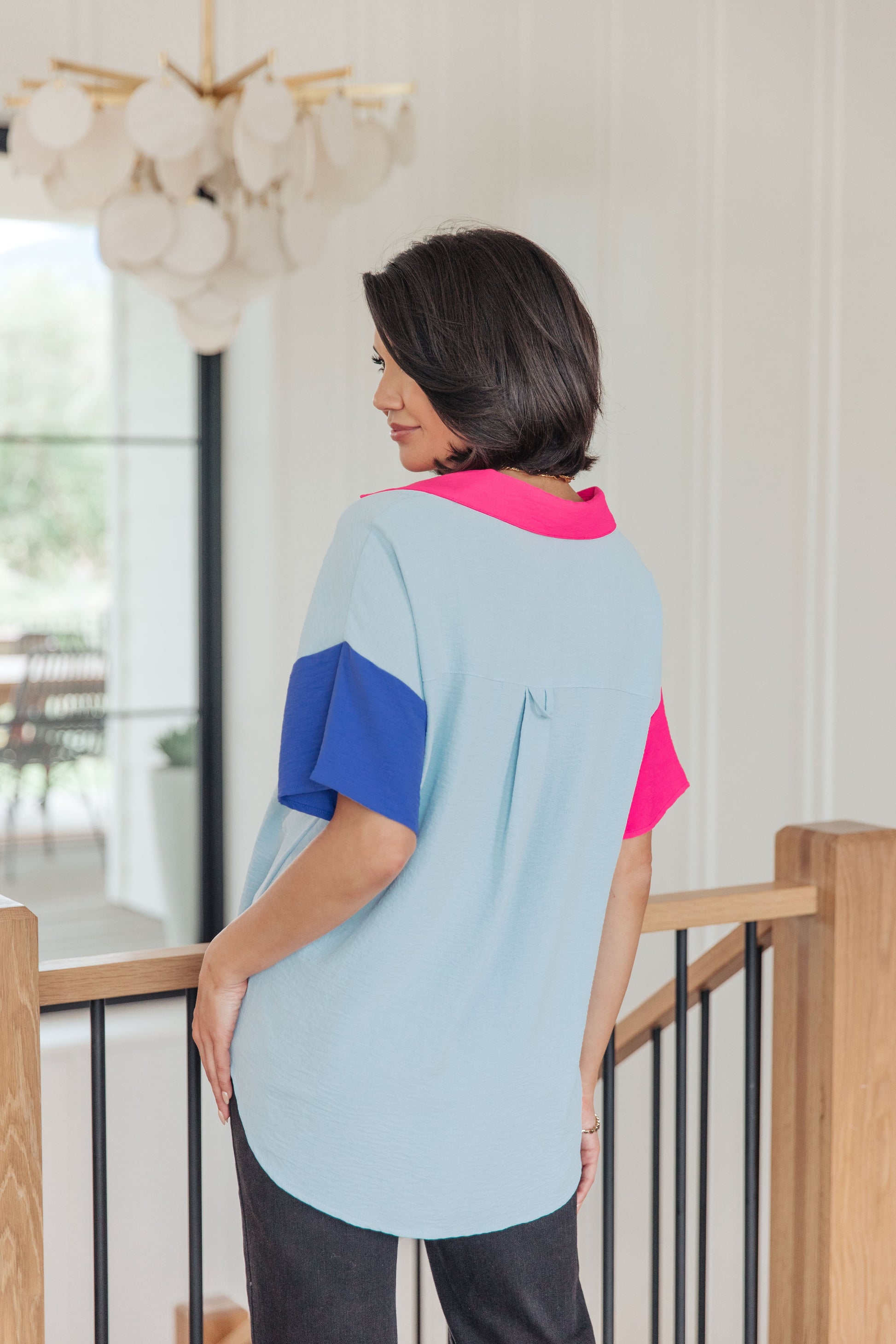 Woman wearing a colorful top standing in a home setting