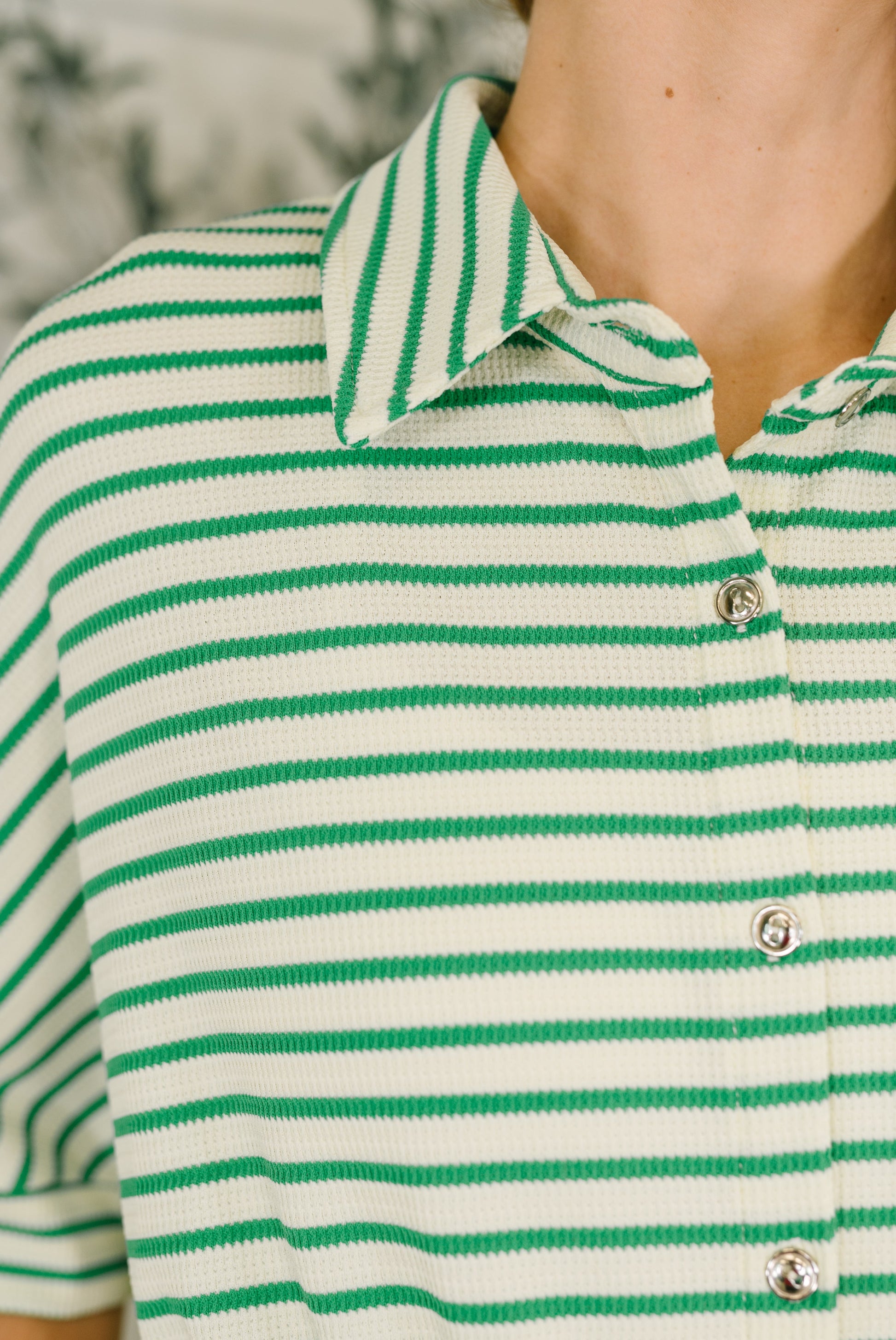 Green and white striped polo shirt with a blurred background