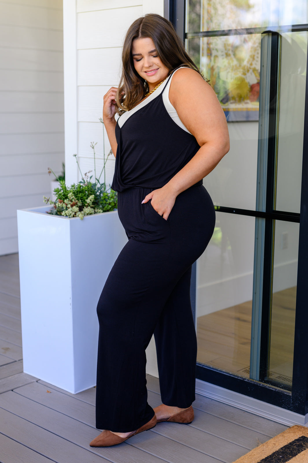 Woman wearing a black and white outfit standing on a wooden deck.
