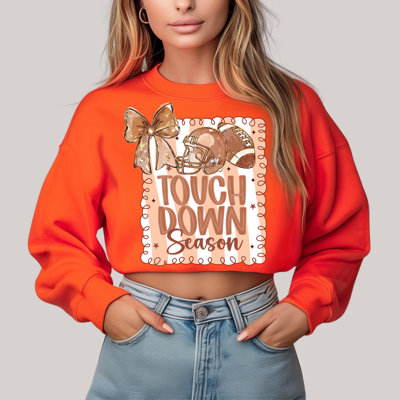 Person wearing an orange sweatshirt with 'Touchdown Season' design on a plain background