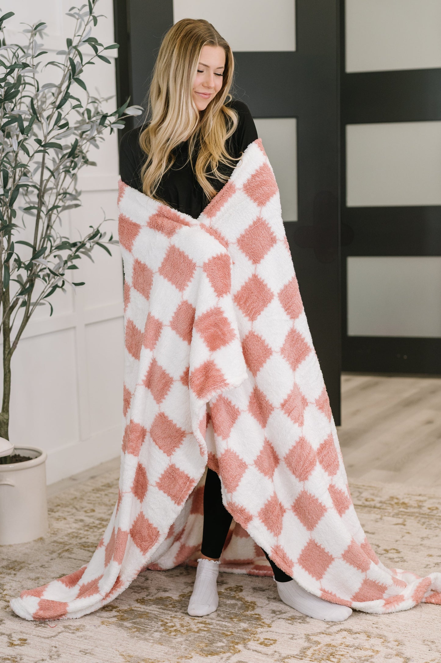 Woman wrapped in a pink and white checkered blanket indoors.