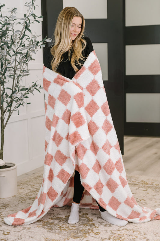 Woman wrapped in a pink and white checkered blanket indoors.