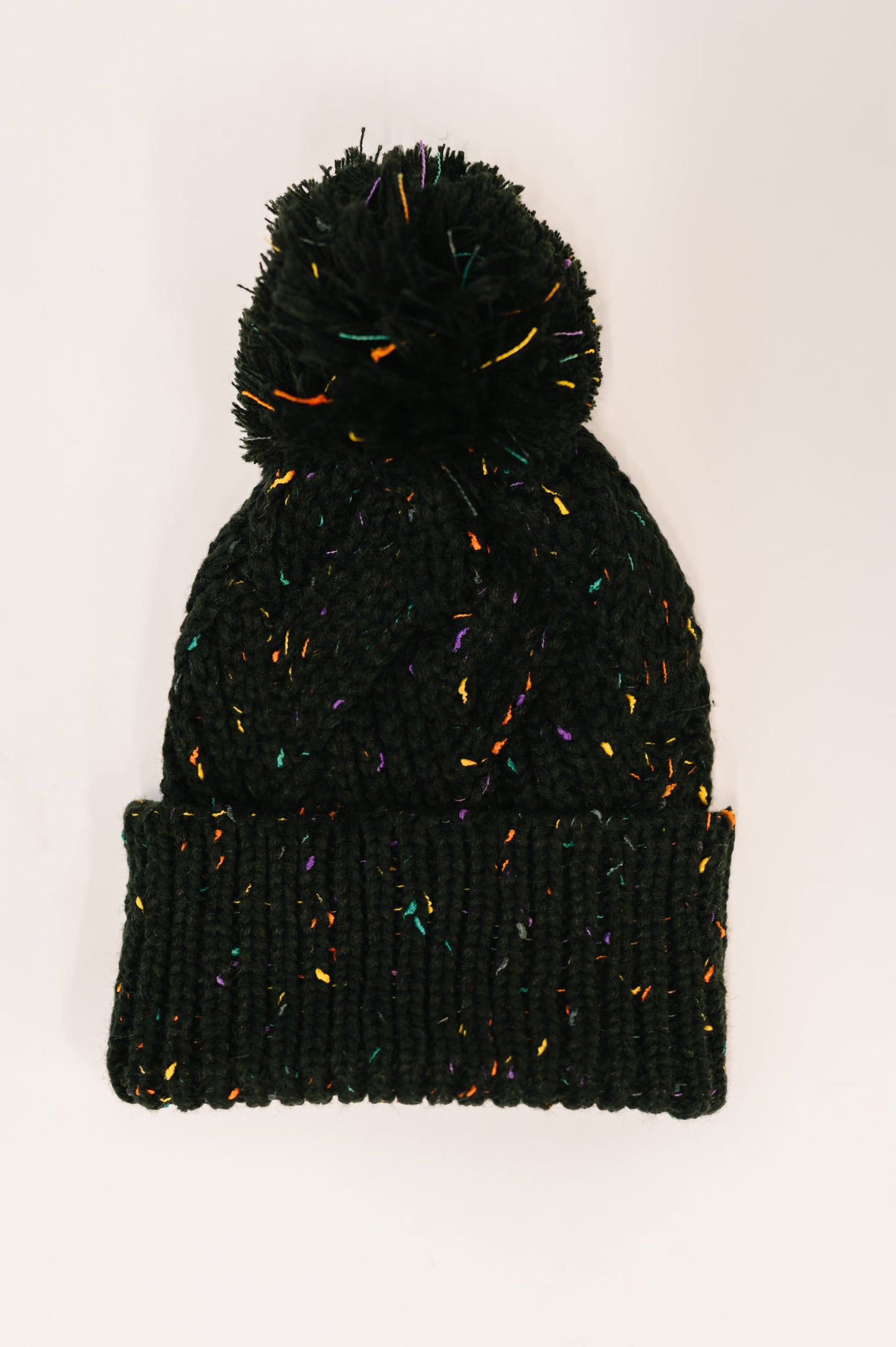 Black knit beanie with colorful speckles on a white background