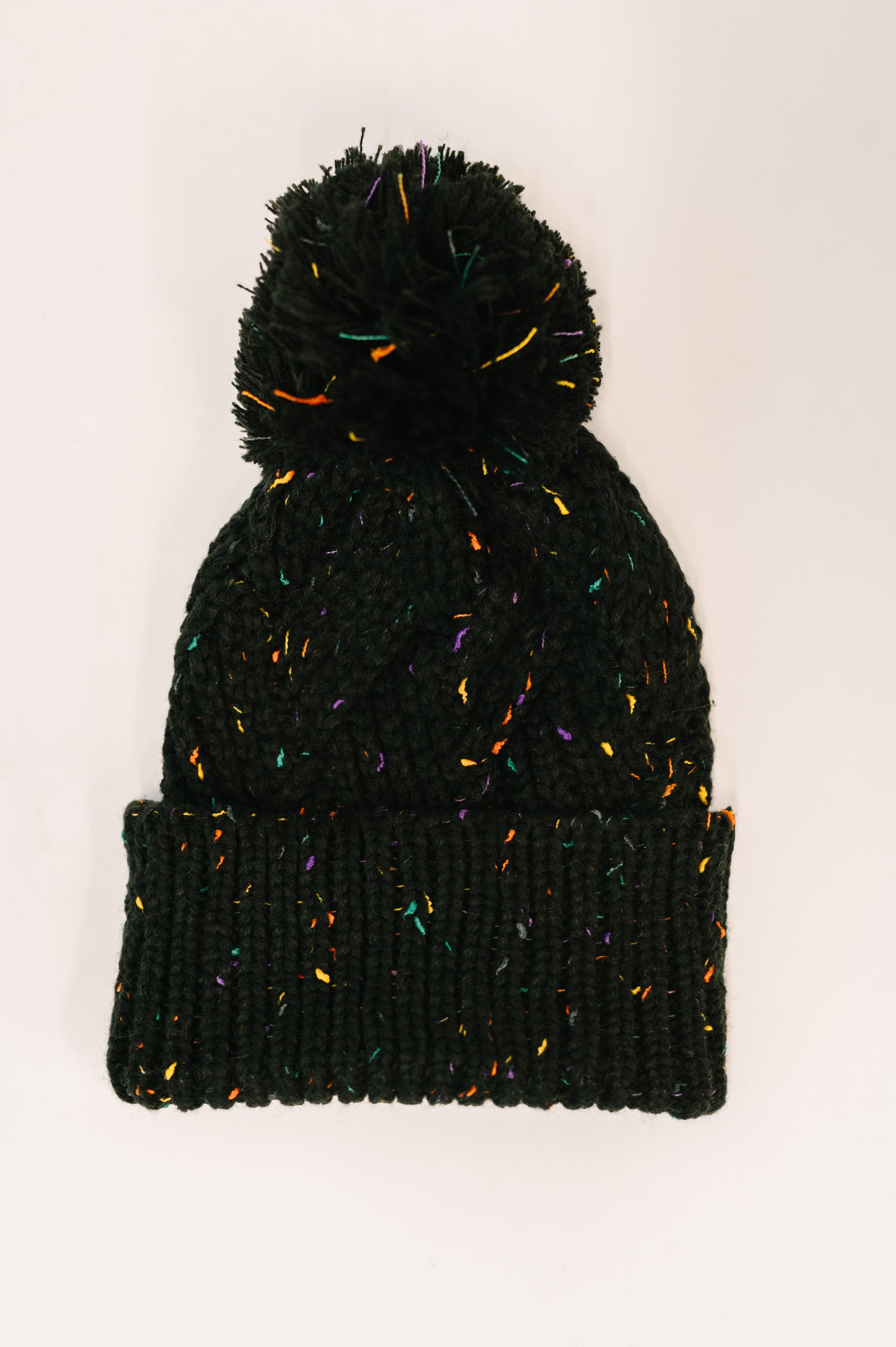 Black knit beanie with colorful speckles on a white background