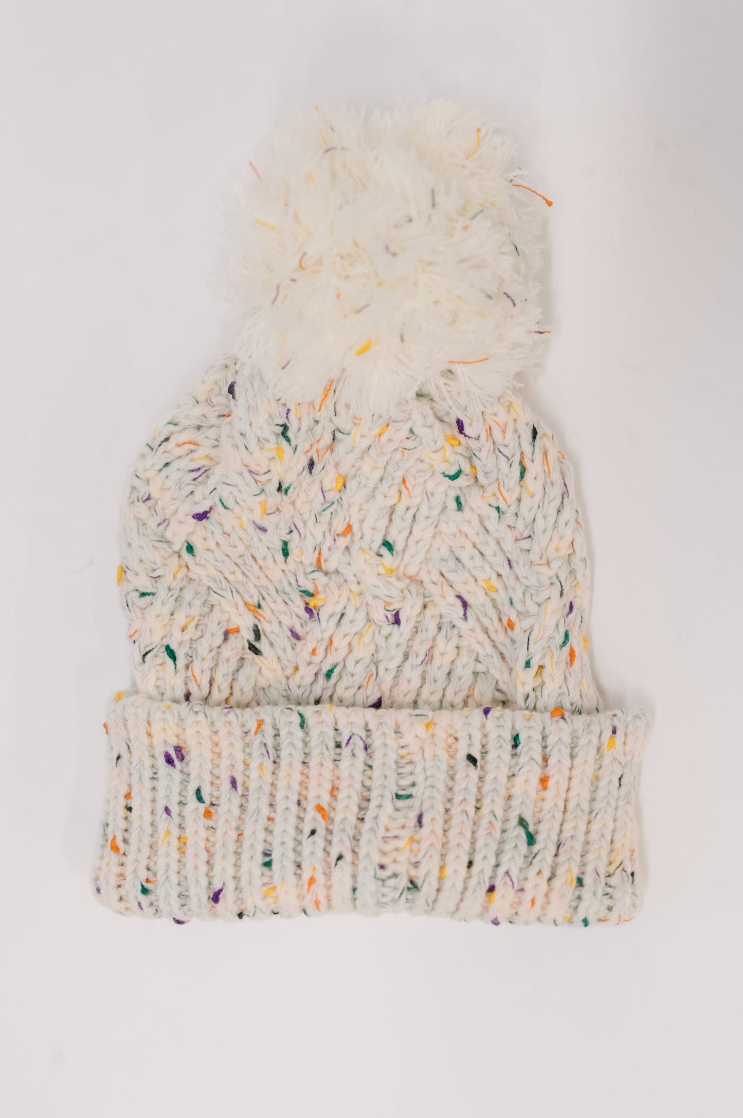 Knitted beanie with colorful speckles and a pom-pom on a white background