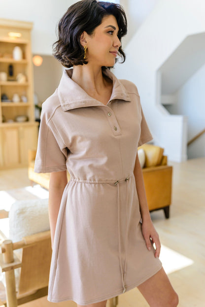 Woman wearing a beige dress in a living room setting