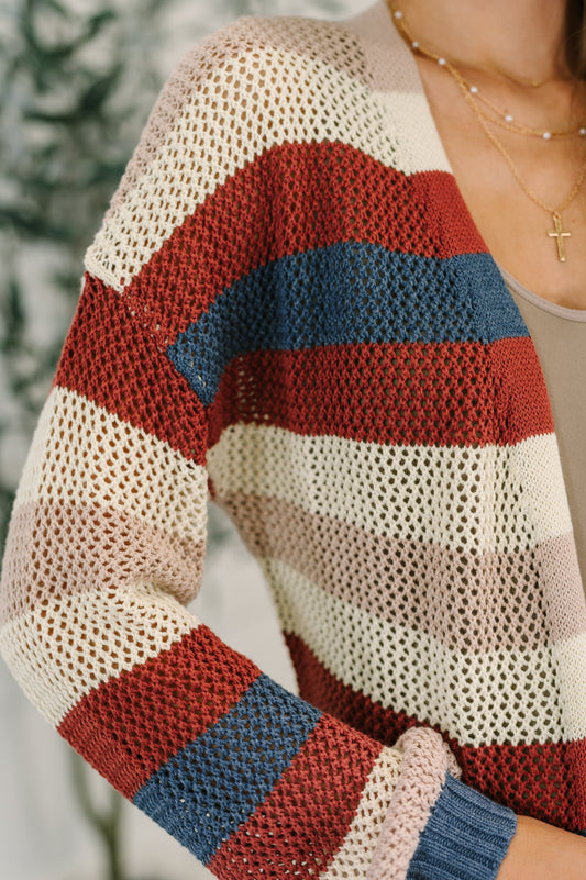 Close-up of a person wearing a knitted cardigan with red, blue, and beige stripes.