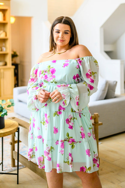 Woman wearing a floral off-shoulder dress in a living room setting