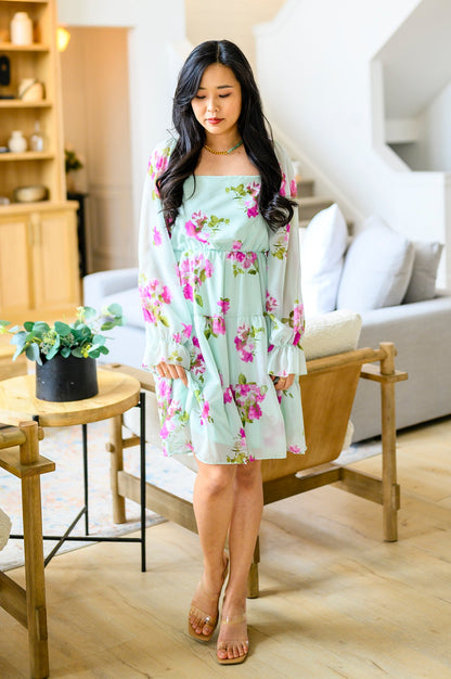 Woman in a floral dress standing in a living room.