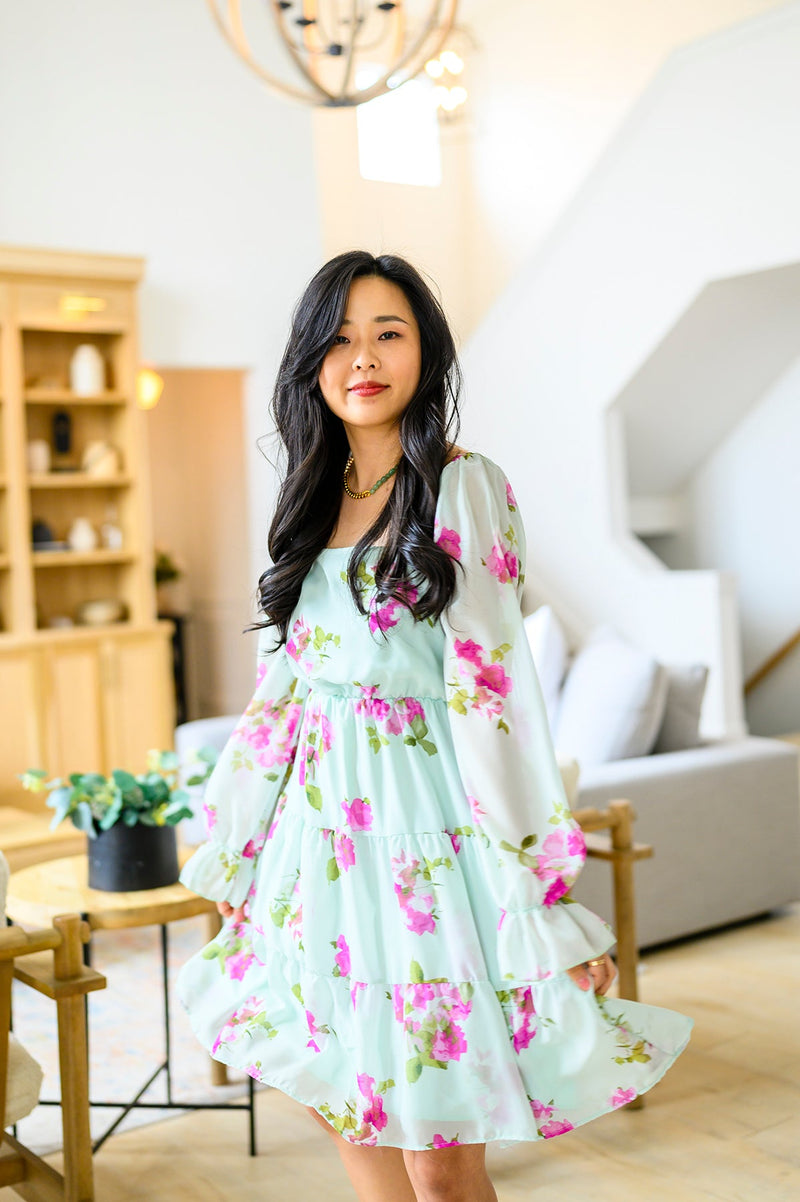 Woman in a floral dress standing in a modern living room.