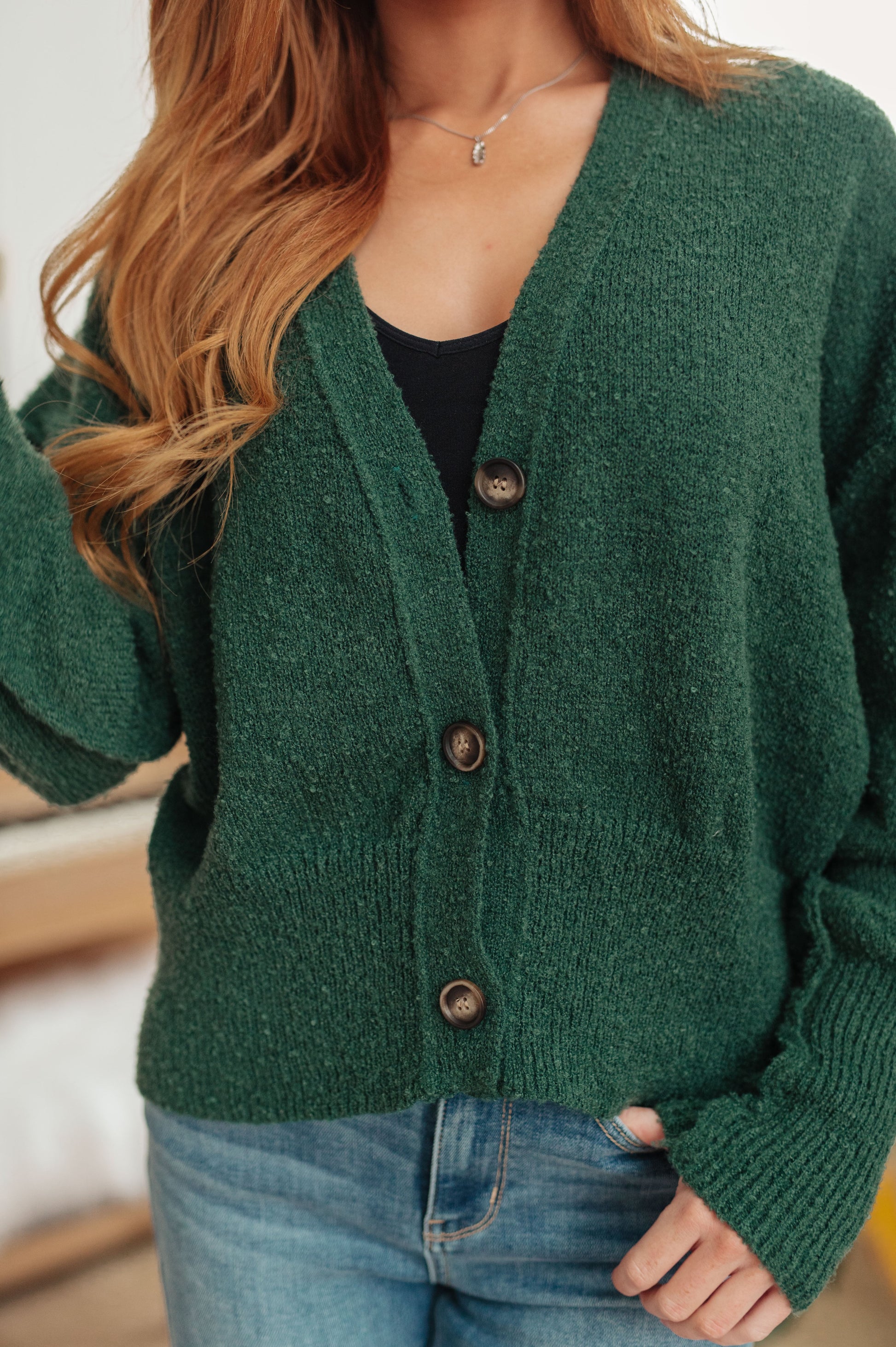 Person wearing a green cardigan with a blurred background