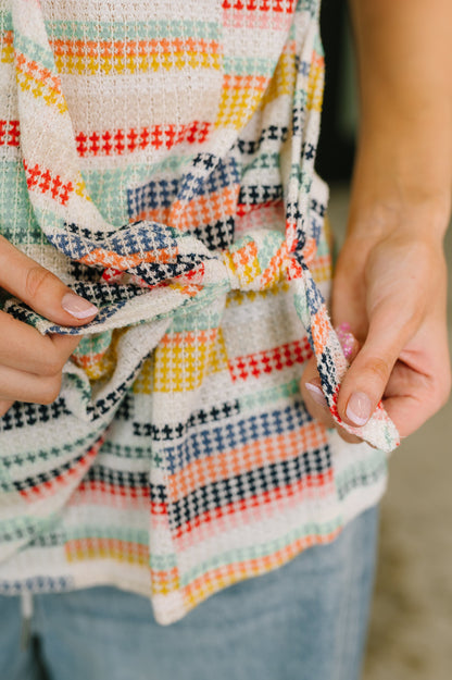 Close-up of a colorful plaid fabric held by hands with a blurred background