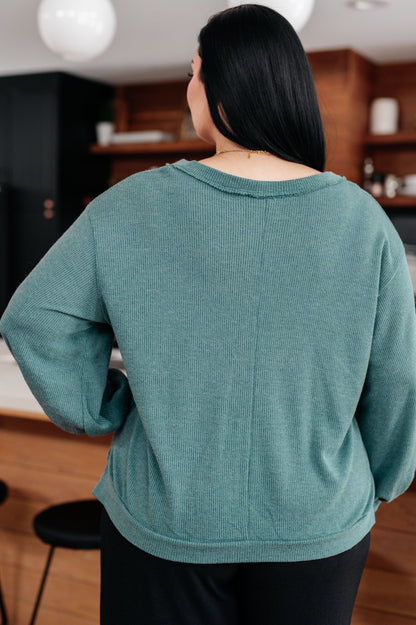 Person wearing a teal sweater in an indoor setting