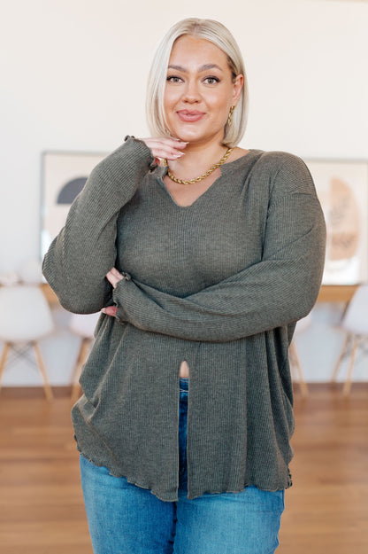 Woman wearing a green sweater and blue jeans indoors