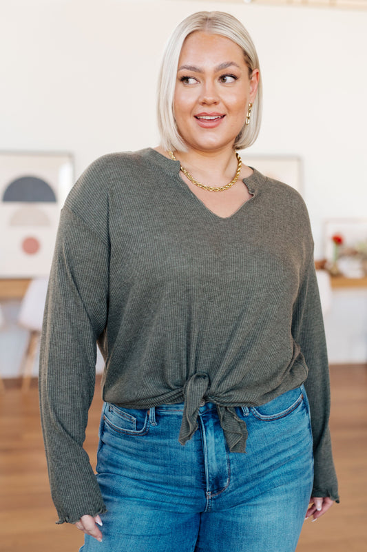 Woman wearing a green sweater and blue jeans indoors
