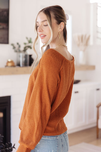 Woman wearing a rust-colored sweater in a kitchen setting