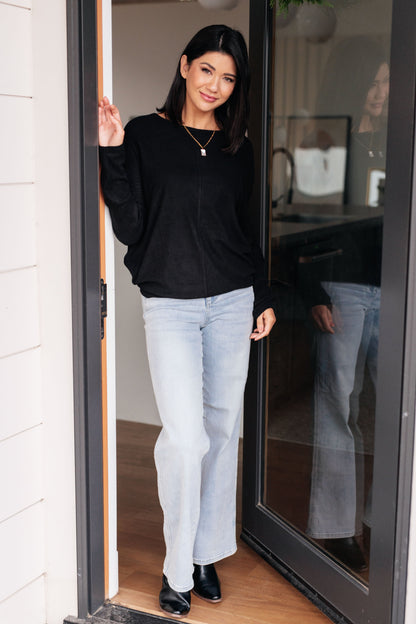 Woman in black top and light blue jeans standing in a doorway.