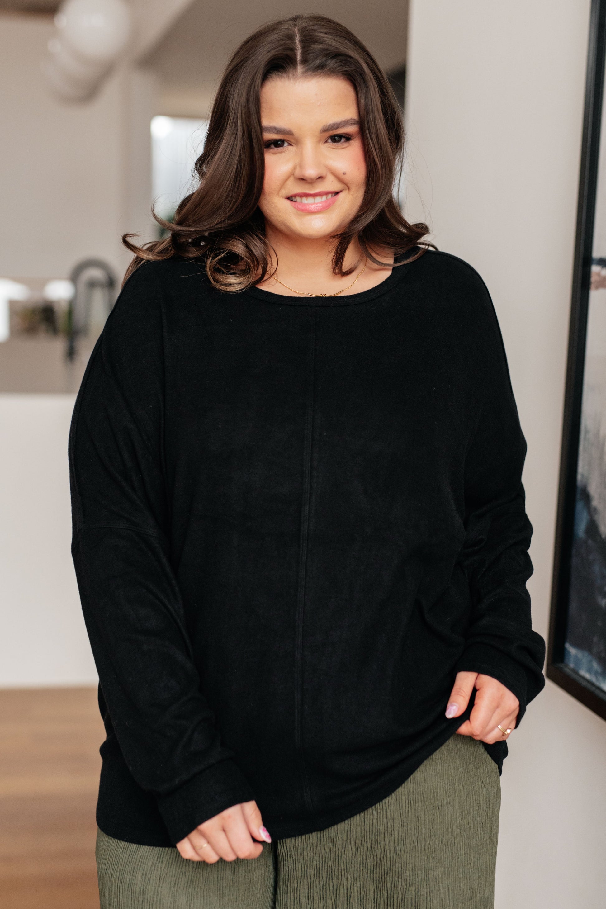 Woman wearing a black sweater and green pants indoors