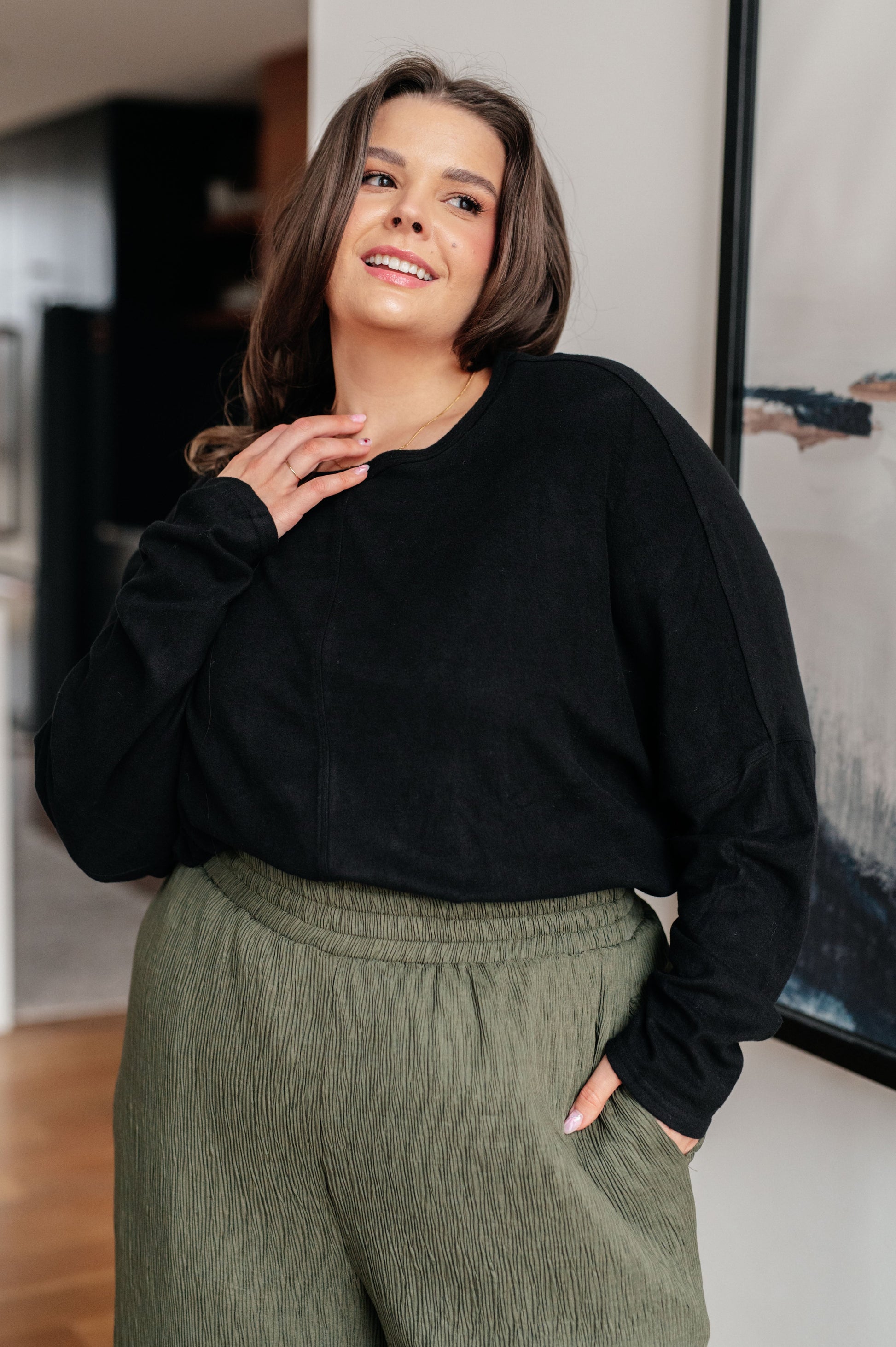 Woman wearing a black sweater and green pants indoors