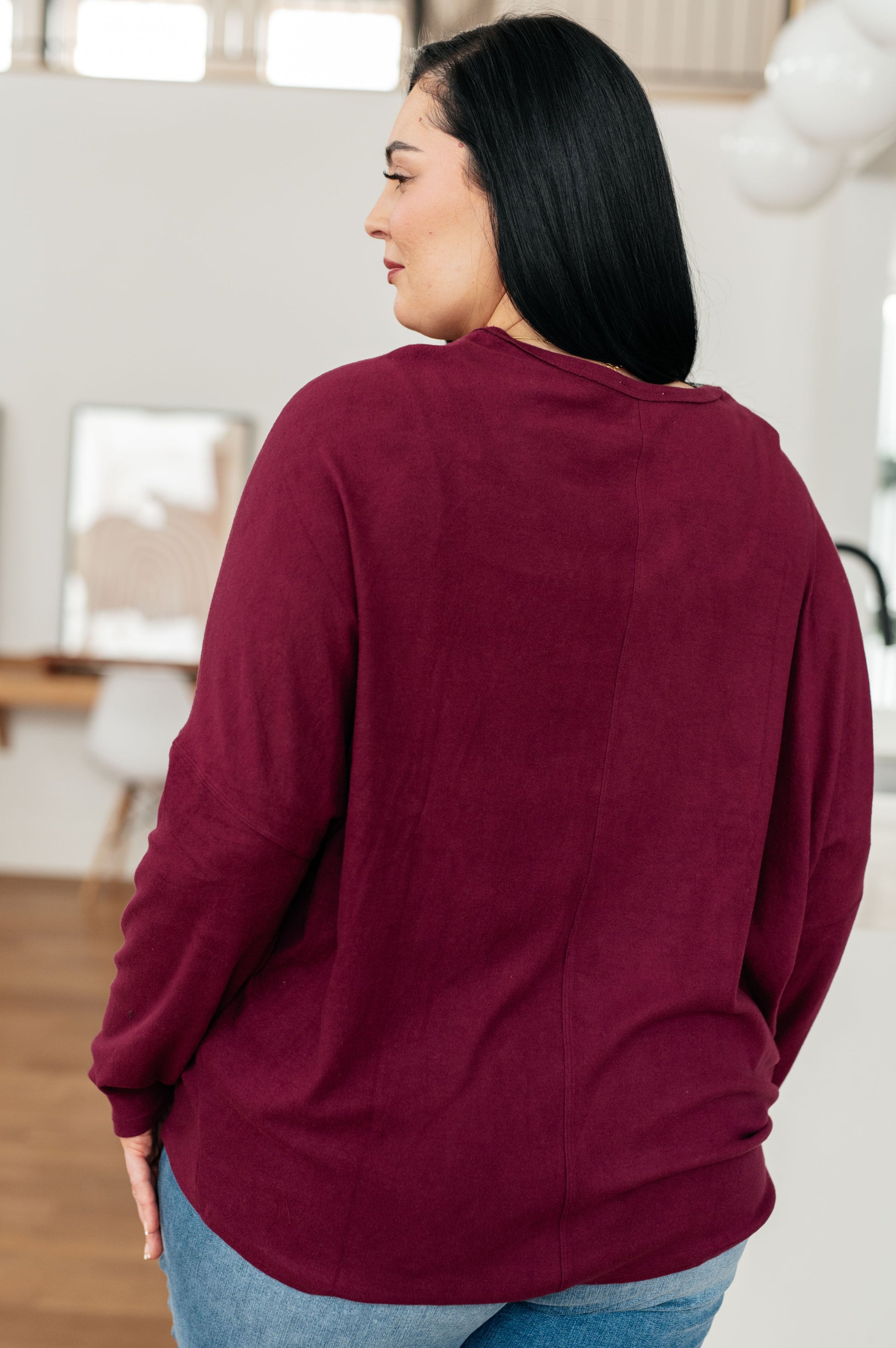 Person wearing a burgundy sweater in an indoor setting