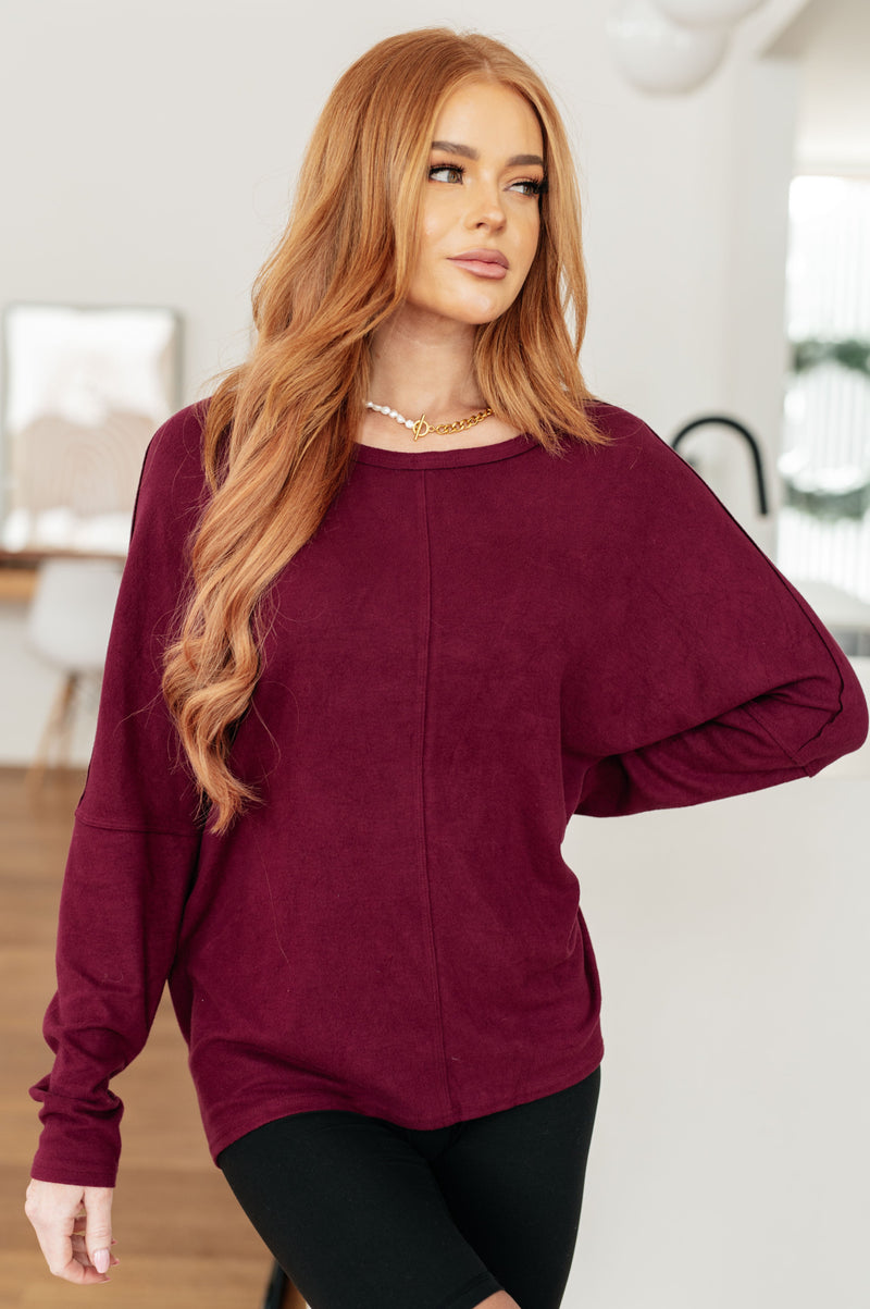Woman wearing a burgundy sweater in a bright room